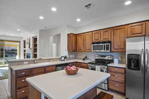 Kitchen with brown cabinets, stainless steel appliances, a peninsula, tasteful backsplash, and recessed lighting