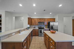 Kitchen featuring stainless steel appliances, brown cabinetry, light countertops, recessed lighting, and tasteful backsplash
