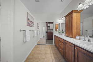Full bath featuring double vanity and light tile patterned floors
