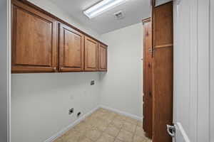 Laundry area featuring cabinet space, washer hookup, electric dryer hookup, and light tile patterned floors