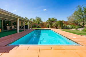 View of swimming pool with a fenced backyard, a putting green, a patio area, and a sunroom