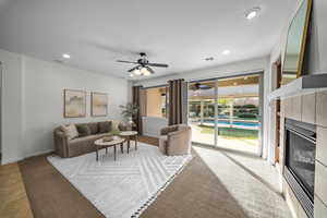 Living area with a tile fireplace, light colored carpet, recessed lighting, and ceiling fan