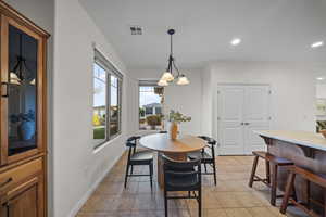 Dining space with light tile patterned flooring, recessed lighting, and a chandelier