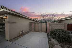 View of property exterior with a gate, stucco siding, and a patio area