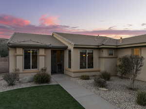 Exterior entry at dusk featuring stucco siding and a tile roof