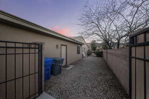 Property exterior at dusk featuring stucco siding and a gate