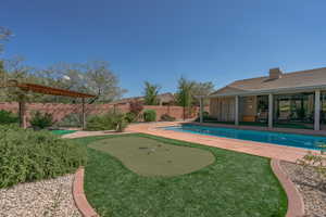 View of pool with an area to practice putting, a fenced backyard, and a patio area