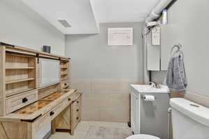 Bathroom with vanity, tile walls and floor, and a textured ceiling
