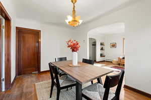Dining space with wood finished floors, arched walkways, and a chandelier