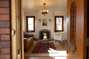Sitting room featuring a chandelier, plenty of natural light, a fireplace, and wood finished floors