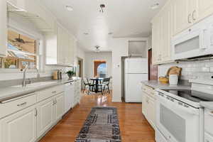 Kitchen featuring white appliances, light wood-style floors, light countertops, white cabinetry, and recessed lighting