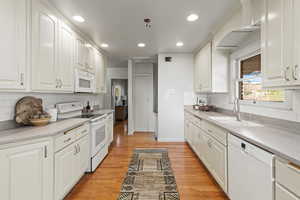 Kitchen featuring white appliances, recessed lighting, light wood finished floors, white cabinetry, and tasteful backsplash