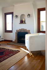 Living area featuring a stone fireplace, wood finished floors, and baseboard heating