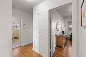 Hall featuring light wood-style floors and a baseboard heating unit