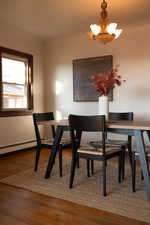 Dining space featuring wood finished floors, baseboard heating, and a chandelier