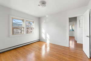 Empty room with a baseboard radiator and light wood-type flooring