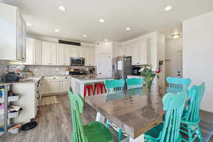 Kitchen featuring a center island, tasteful backsplash, light stone counters, dark wood-style floors, and stainless steel appliances