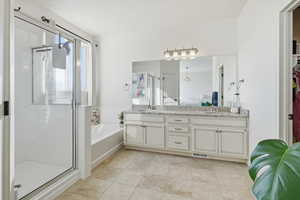 Ensuite bathroom with a shower stall, double vanity, a bath, and a spacious closet