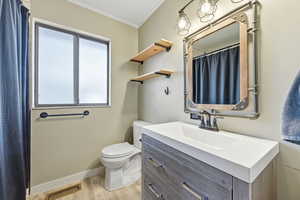Full bath with crown molding, curtained shower, vanity, and light wood-style flooring