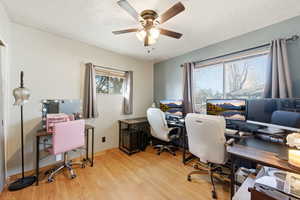 Home office featuring light wood-style flooring, a ceiling fan, and a textured ceiling