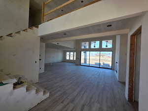Unfurnished living room with wood finished floors and a high ceiling
