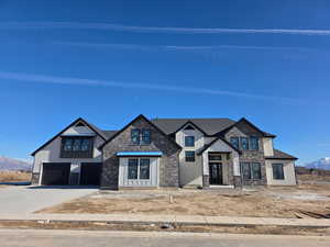 View of front of home with a mountain view, concrete driveway, stone siding, an attached garage, and stucco siding