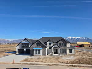 View of front of property featuring a mountain view, stone siding, concrete driveway, and a garage
