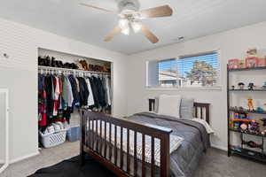 Bedroom with carpet, a closet, and a ceiling fan