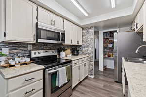 Kitchen featuring stainless steel appliances, light countertops, white cabinetry, and light wood-type flooring