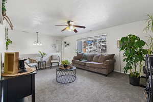 Living area featuring carpet floors, ceiling fan, a textured ceiling, and a chandelier
