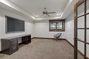 Unfurnished office featuring light colored carpet, recessed lighting, a ceiling fan, and a raised ceiling
