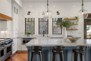 Kitchen featuring decorative backsplash, range with two ovens, white cabinets, and plenty of natural light