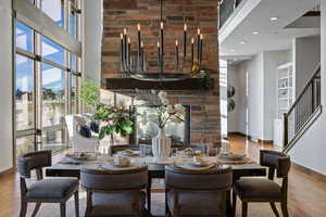 Dining area with a towering ceiling, wood finished floors, stairway, and a glass covered fireplace