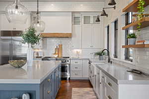 Kitchen featuring white cabinets, light stone counters, pendant lighting, open shelves, and high quality appliances