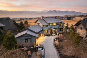 View of front of property with stone siding, driveway, a mountain view, a chimney, and a residential view