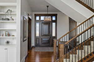 Entryway featuring dark wood finished floors and a chandelier