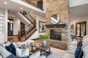 Living room with wood finished floors, a brick fireplace, recessed lighting, a towering ceiling, and french doors