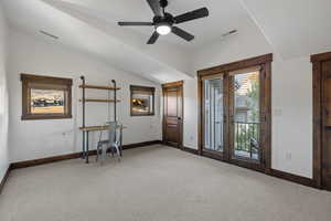 Interior space featuring light colored carpet, ceiling fan, lofted ceiling, and french doors