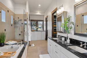 Bathroom with double vanity, a stall shower, a bath, and light tile patterned floors