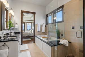 Ensuite bathroom featuring a shower stall, double vanity, a garden tub, light tile patterned floors, and a tray ceiling
