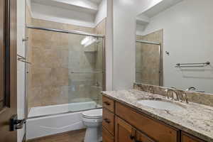 Full bathroom featuring vanity, combined bath / shower with glass door, and dark wood finished floors