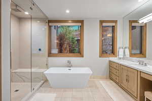 Bathroom featuring a tile shower, a freestanding bath, vanity, light tile patterned floors, and recessed lighting