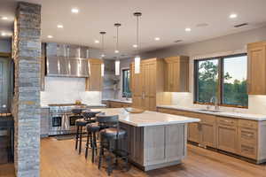 Kitchen featuring hanging light fixtures, tasteful backsplash, light stone counters, double oven range, and recessed lighting