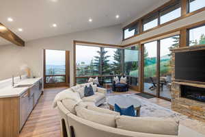 Living room with recessed lighting, lofted ceiling, light wood finished floors, and a fireplace