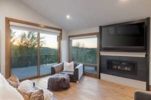 Living room featuring hardwood / wood-style flooring, a large fireplace, lofted ceiling, and recessed lighting