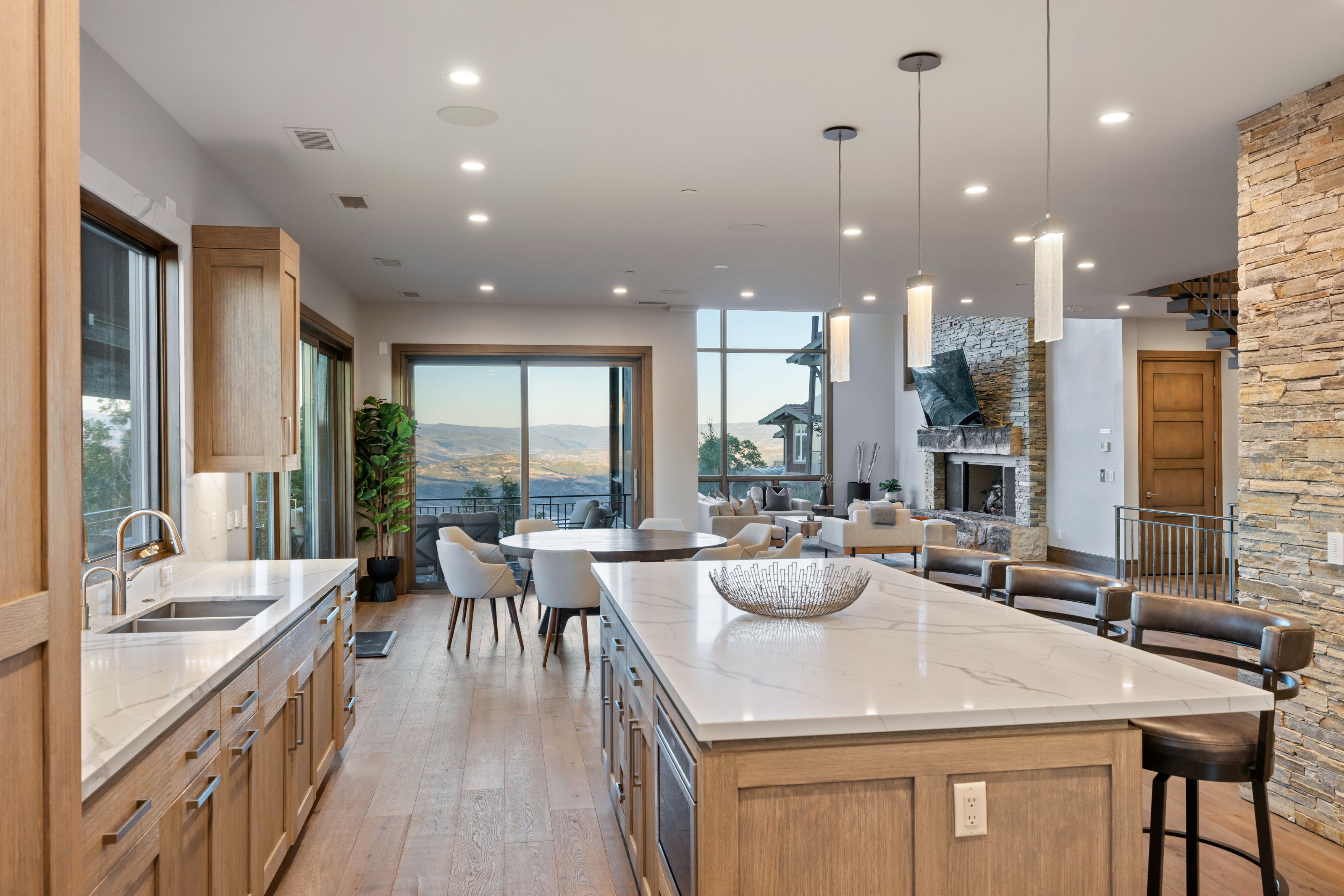 Kitchen with light stone counters, light brown cabinetry, hanging light fixtures, and recessed lighting