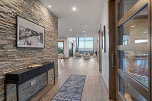 Corridor featuring recessed lighting, light wood-style flooring, and floor to ceiling windows
