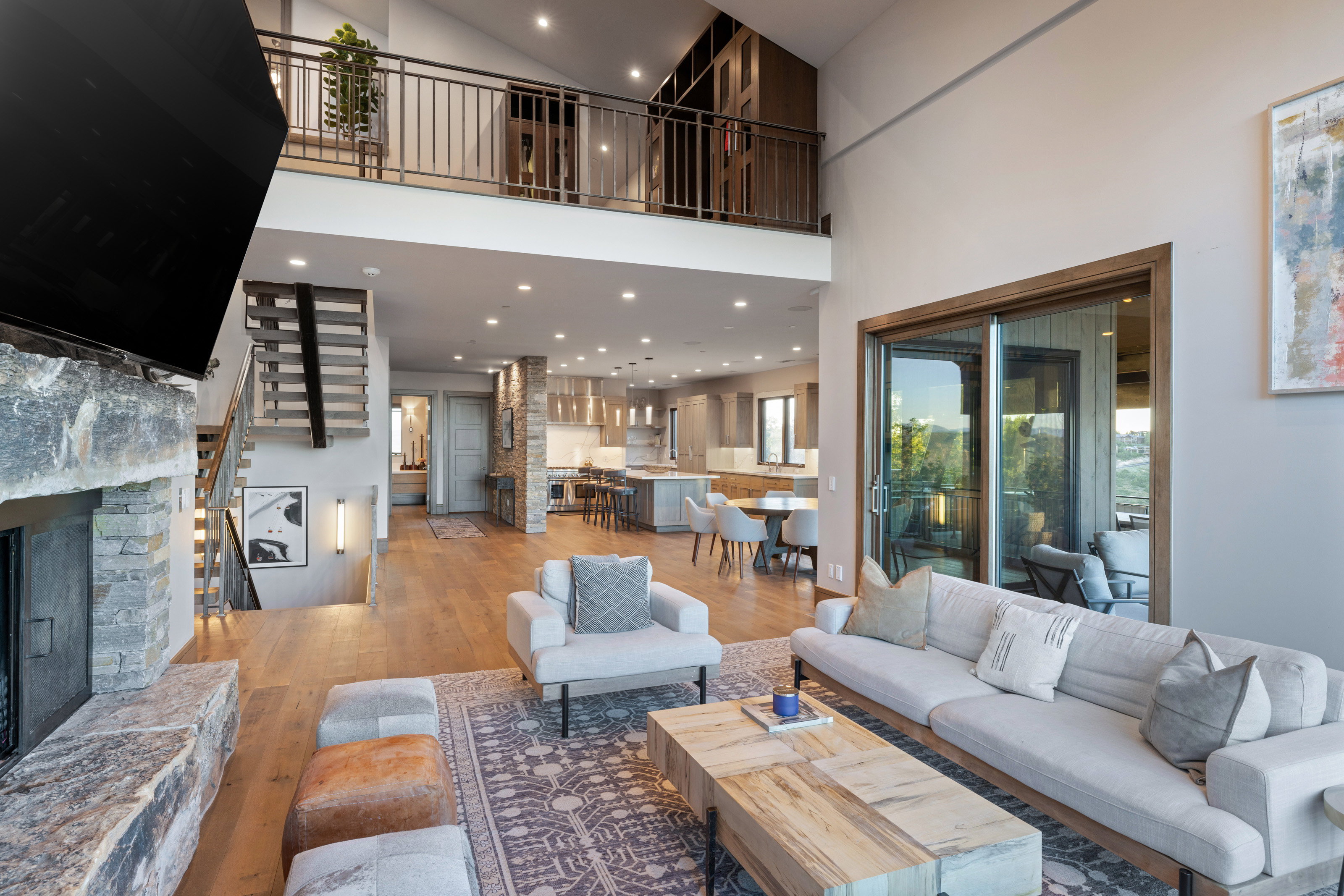 Living room with a fireplace, light wood-style floors, recessed lighting, stairs, and a towering ceiling