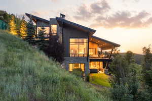 Rear view of house with stone siding and a balcony