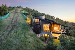 Back of house at dusk with a chimney and stone siding